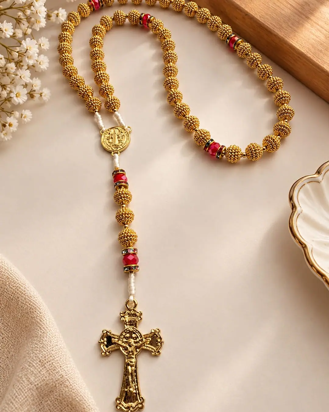 Terço de contas douradas trabalhadas, cristais vermelhos, medalha e crucifixo de São Bento