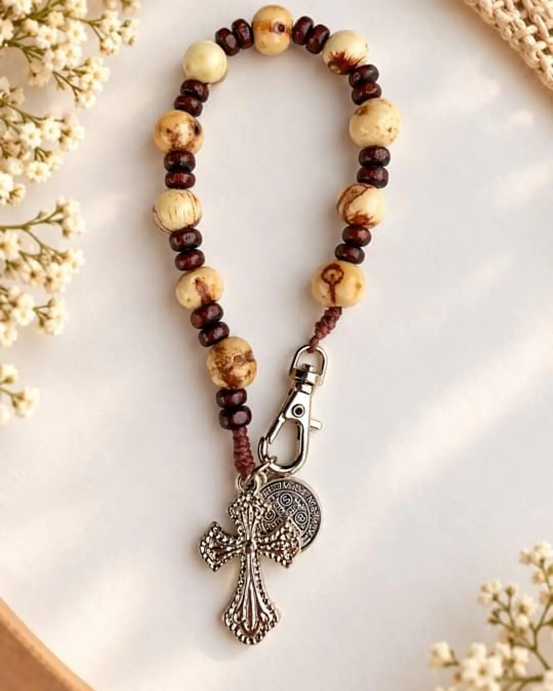 Dezena com contas de madeira clara e escura, mosquetão, medalha e crucifixo prateados